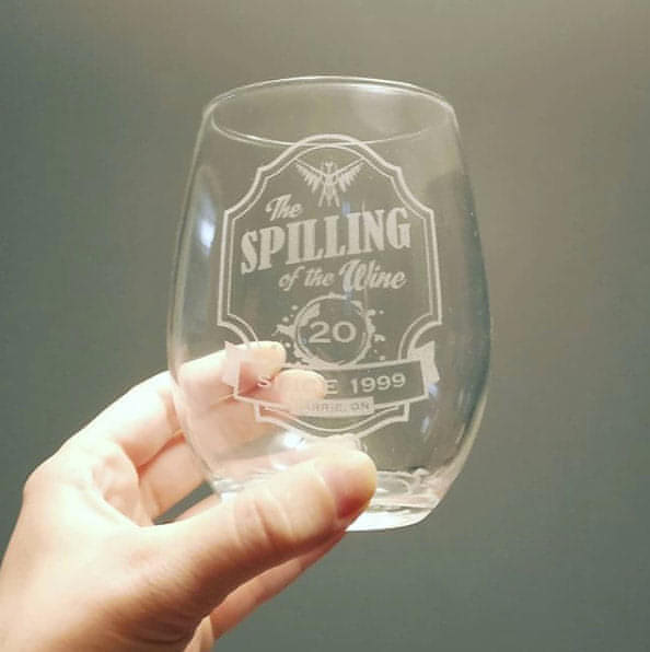 A stemless wine glass engraved with the logo for The Spilling of the Wine