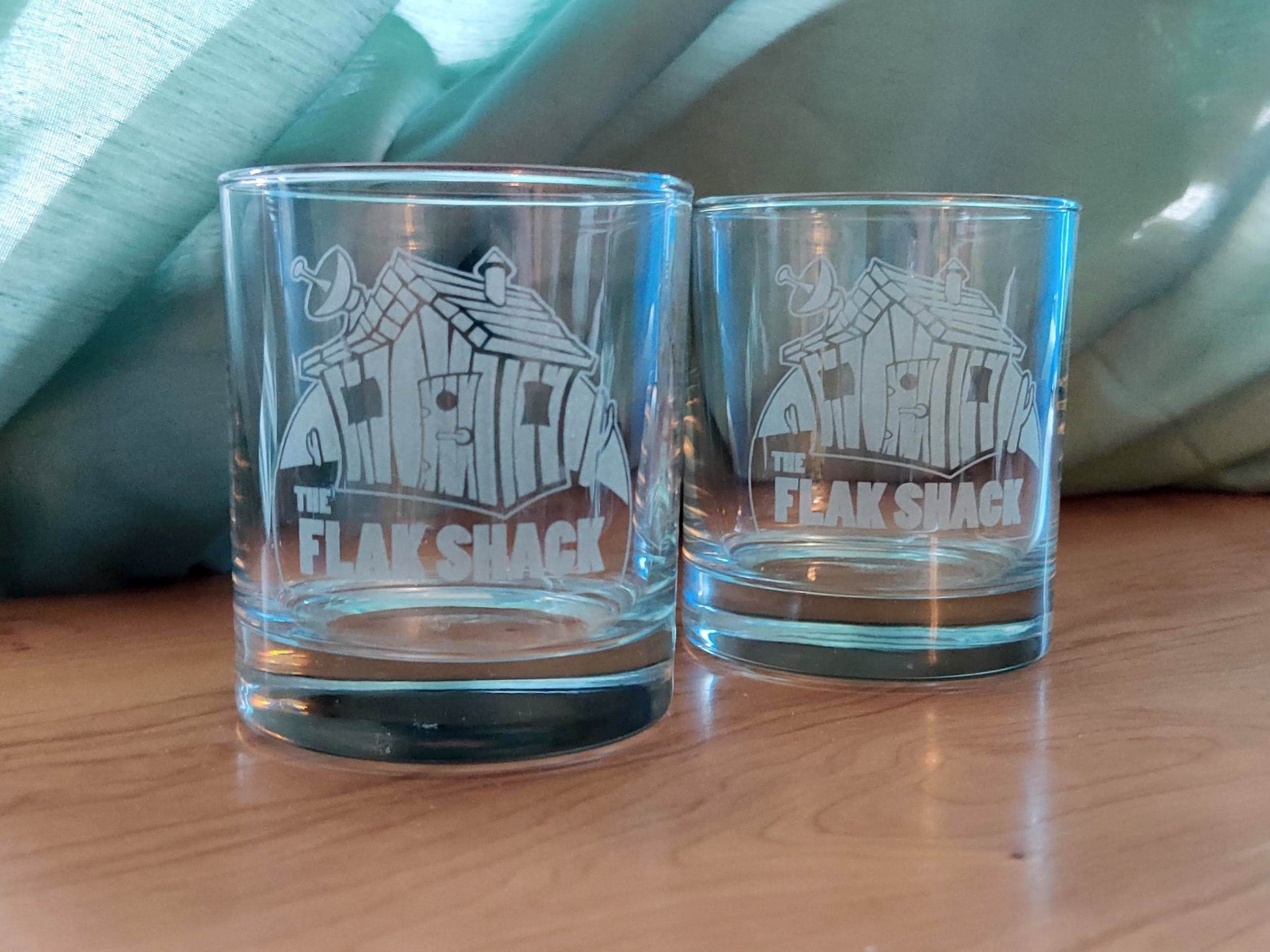 Two whiskey glasses engraved with the logo for The Flak Shack